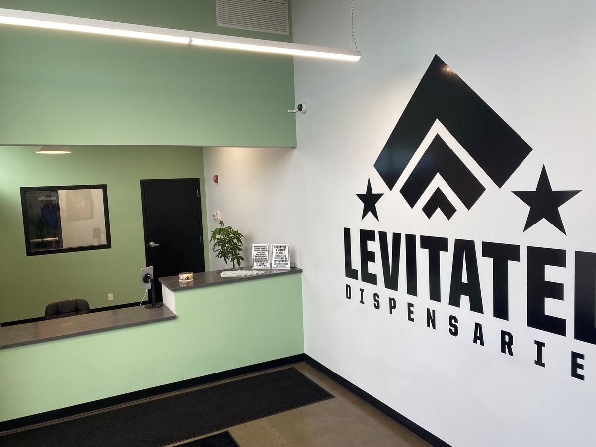 Reception and ID check-in desk inside Levitated Dispensaries in Minneapolis, beside the painted Levitated logo wall