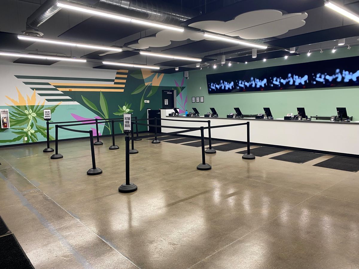 Checkout counter and queue lines on the Levitated Dispensaries sales floor in Minneapolis, with the leaf mural along the wall